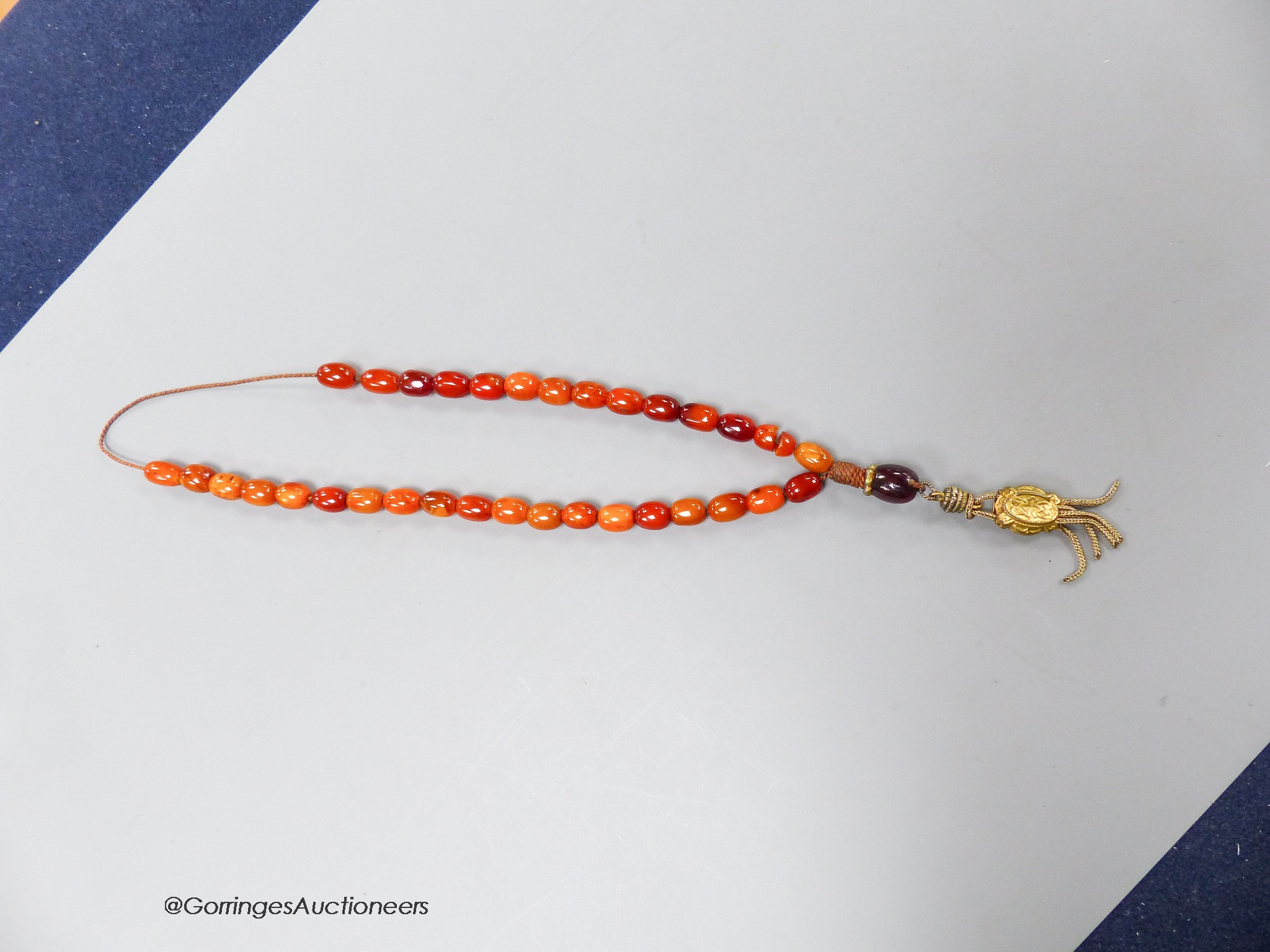 A single strand amber bead necklace, with gilt metal pendant, 36cm, gross weight 12 grams.